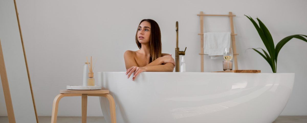 Cadă freestanding albă într-un decor minimalist de baie, cu accente naturale și atmosferă relaxantă