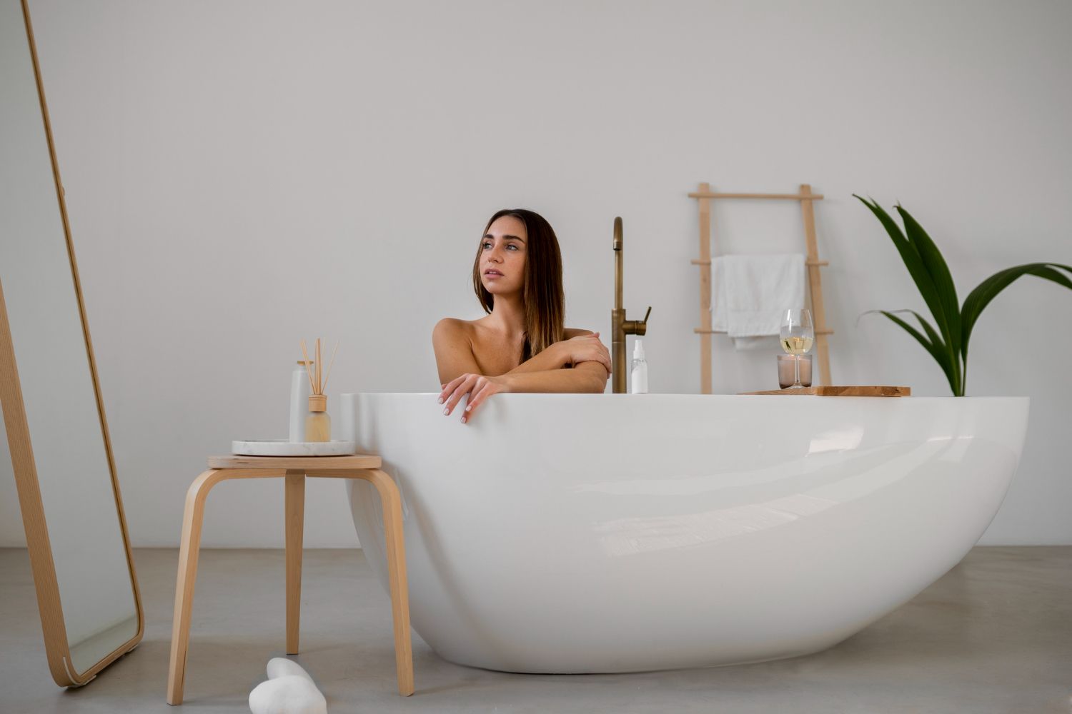 Cadă freestanding albă într-un decor minimalist de baie, cu accente naturale și atmosferă relaxantă